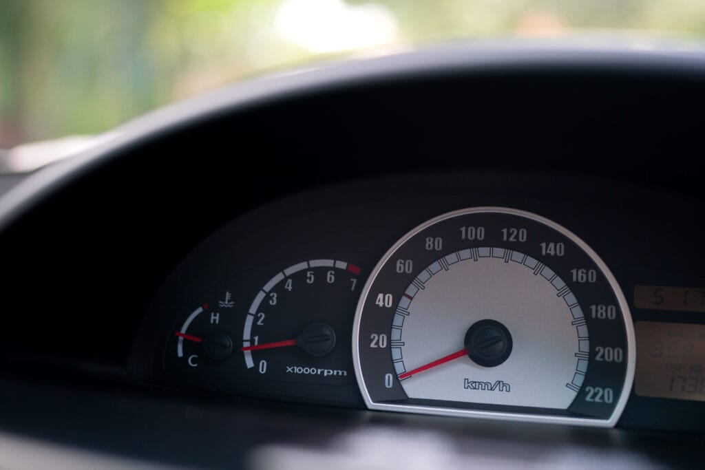 Detailed close-up of a car's speedometer, showcasing the needle pointing to the current speed in a sleek dashboard design.