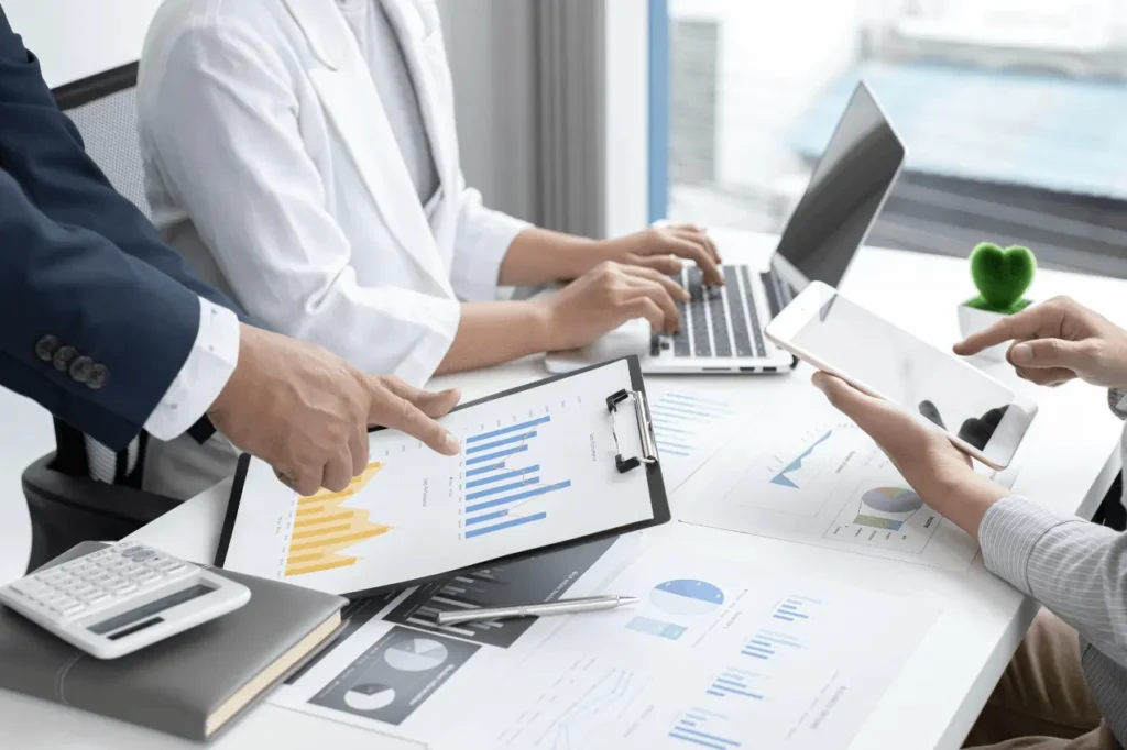 Colleagues reviewing sales reports and charts on a clipboard at a desk